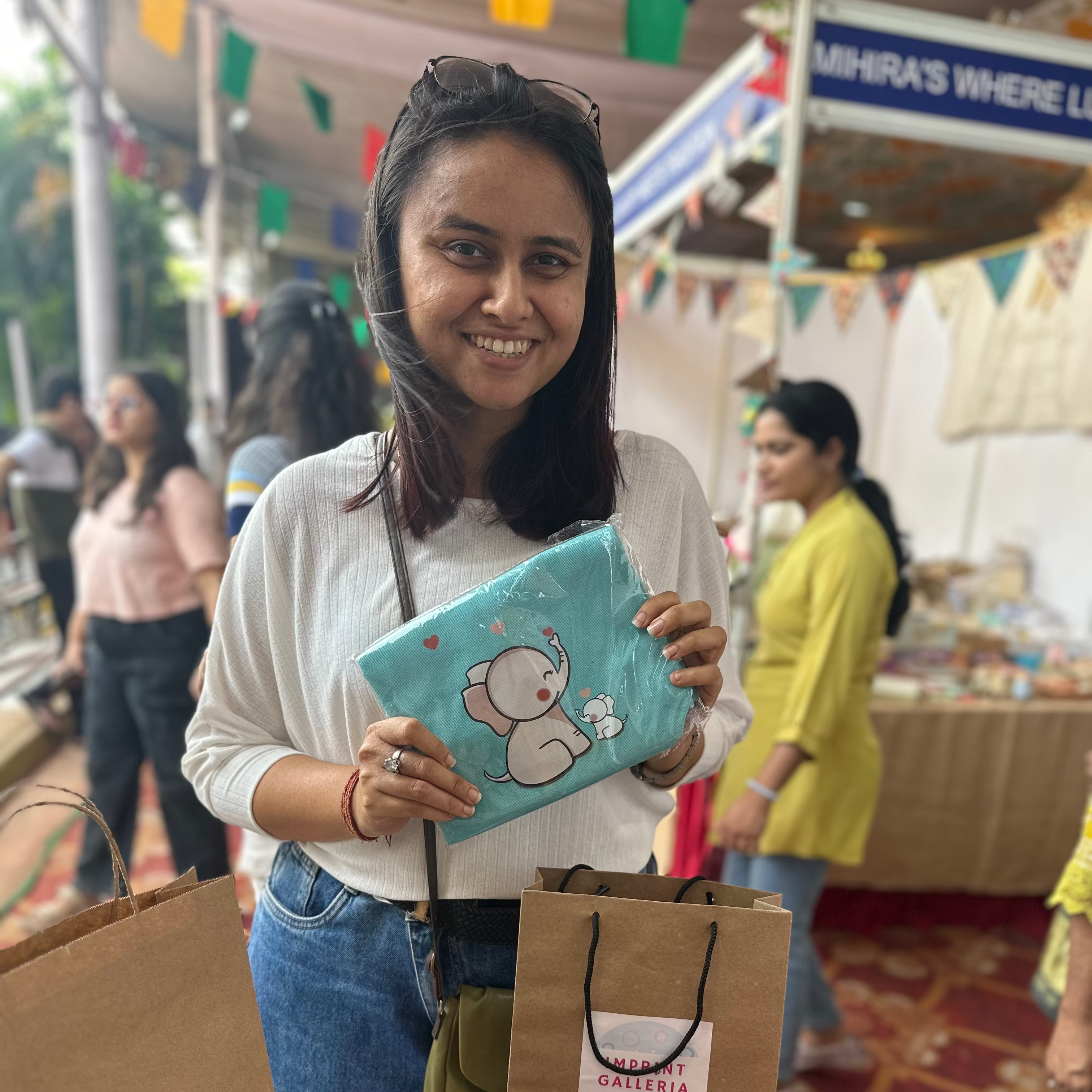 Woman holding a blue pouch with a cartoon design at an outdoor market.
